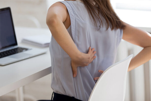 Dieses Bild veranschaulicht eine junge Frau mit Schmerzen im Rücken und Steißbein